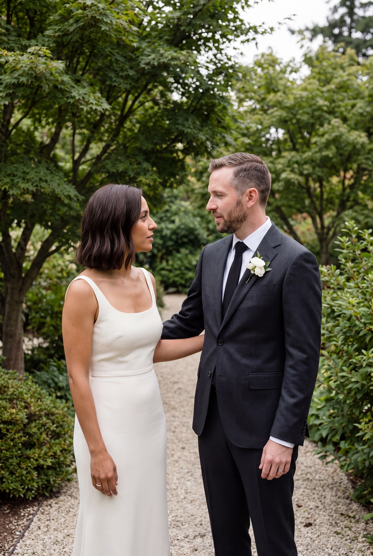 A bride and groom talking together on a narrow garden path