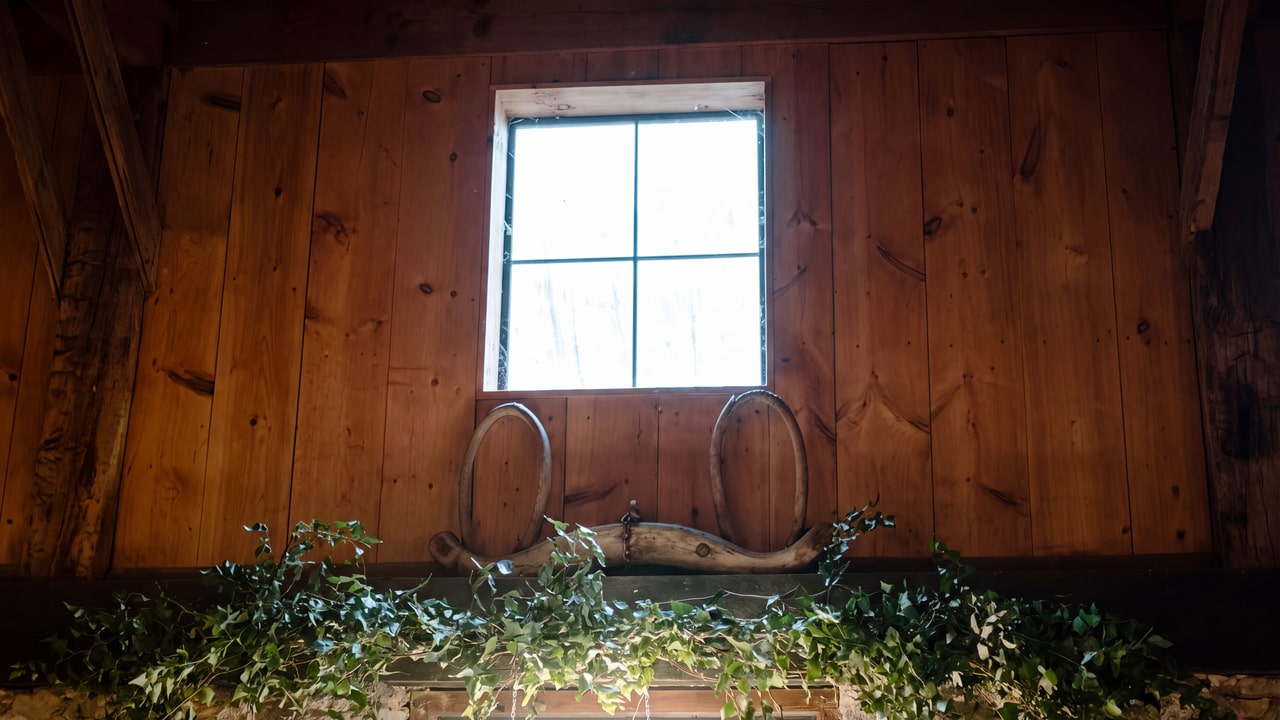 Four-pane window, weathered timber boards and ivy above a stone wall inside the barn at Honsberger Estate.
