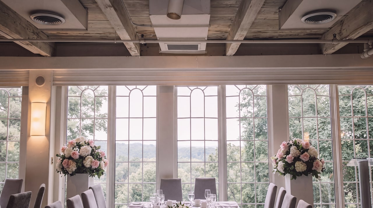 Curved white-framed windows, pale ceiling beams and pink-and-white floral stands at Inn On The Twenty.