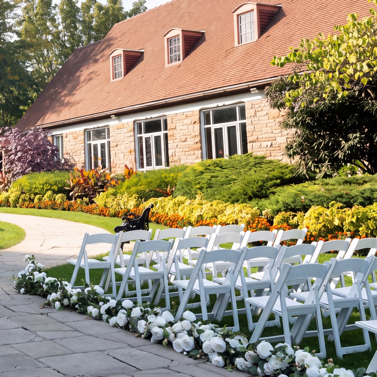 Stone restaurant facade, three red-tiled roof dormers and flower beds beside white ceremony chairs at Queenston Heights.