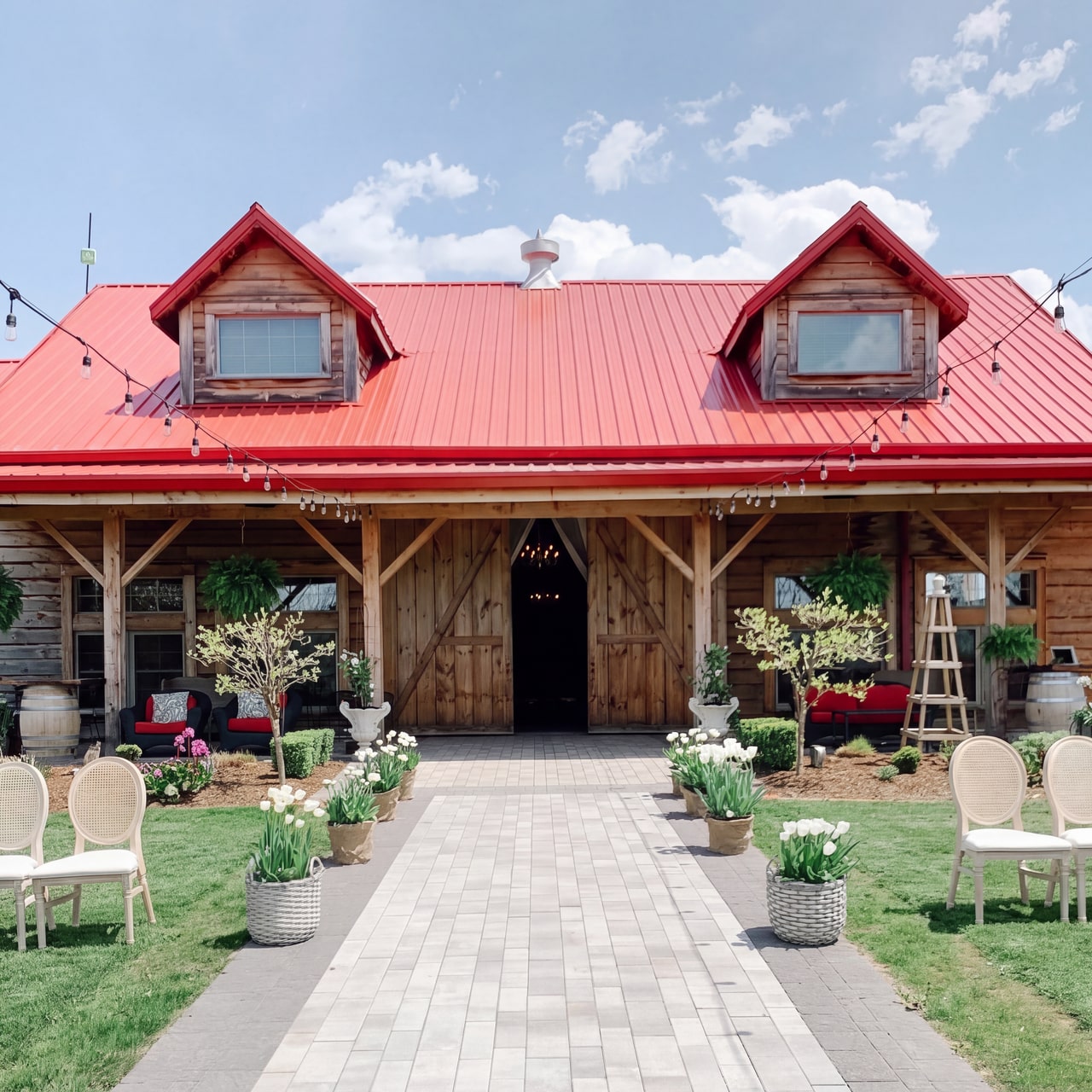 Timber barn with a red roof and two dormers, overlooking a tulip-lined ceremony aisle at Stonewall Estates.